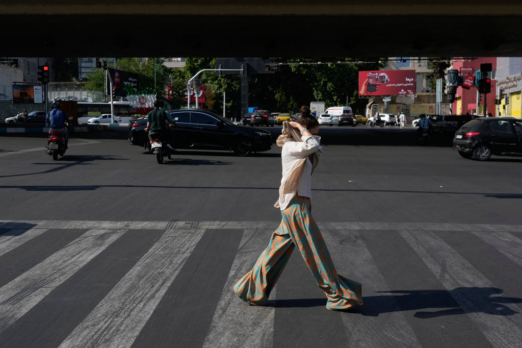 A woman adjusts her headscarf as she crosses an intersection in northern Tehran, Wednesday, June 10, 2026. (AP Photo/Vahid Salemi)