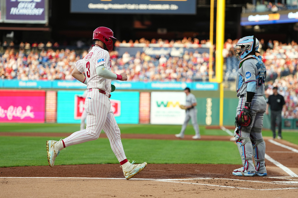 Philadelphia Phillies' Bryce Harper scoots past Miami Marlins catcher Brian Navarreto off of an RBI single by Phillies Alec Bohm during the first inning of a baseball game, Tuesday, Aug. 18, 2026, in Philadelphia. (AP Photo/Matt Rourke)