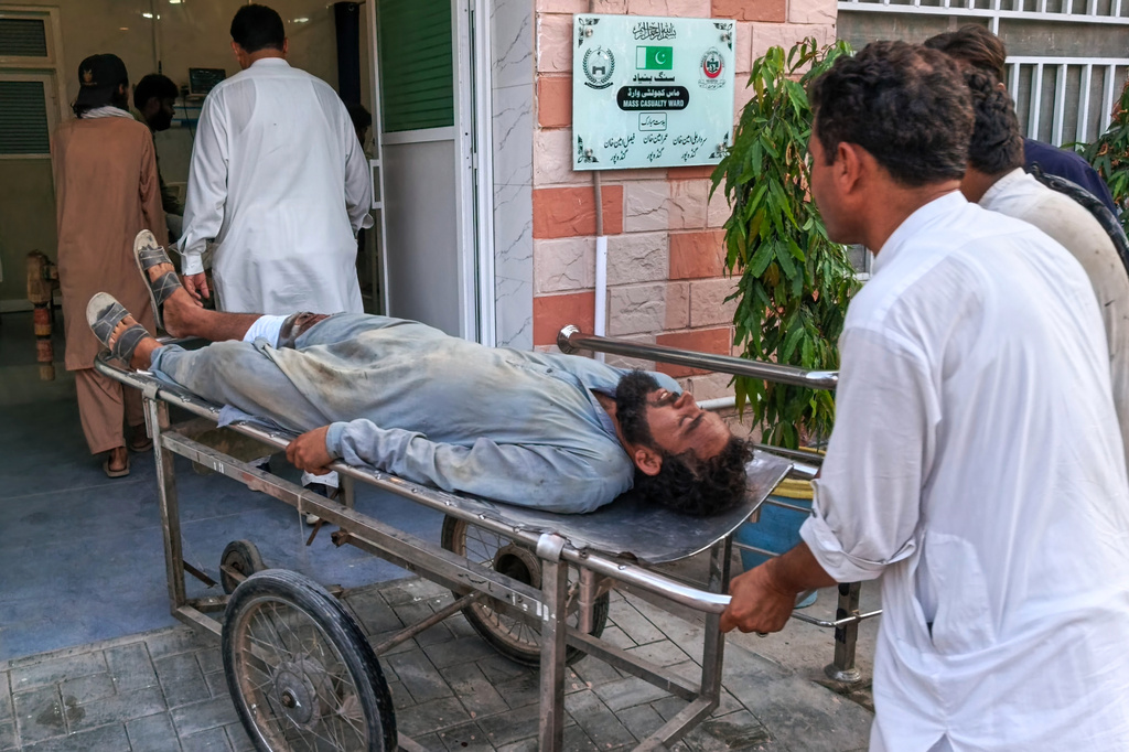 In this photo taken with a smartphone, volunteers transport an injured victim of a suicide attack on a roadside police checkpoint upon his arrival at a hospital in Dera Ismail Khan, Pakistan, Saturday, Sept. 26, 2026. (AP Photo/Kashif Naveed)
