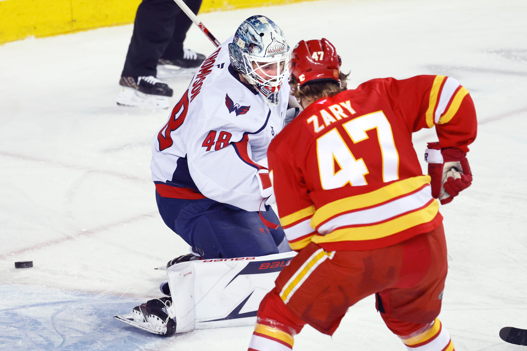 Washington Capitals goalie Logan Thompson (48) makes a save against Calgary Flames' Connor Zary (47) during first-period NHL hockey game action in Calgary, Alberta, Friday, Jan. 23, 2026. (Larry MacDougal/The Canadian Press via AP)