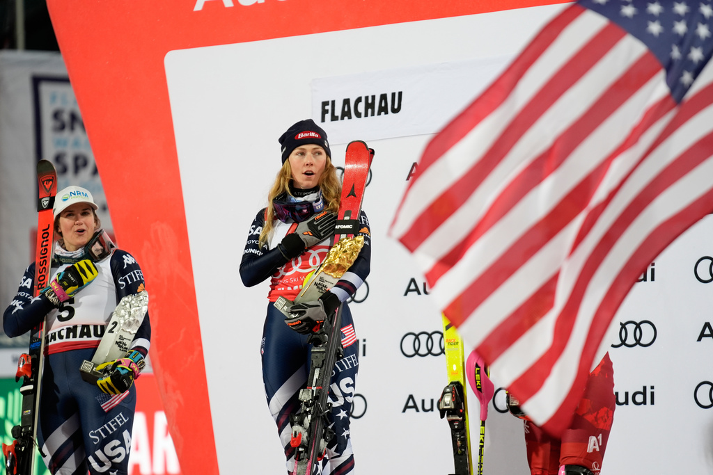 United States' Mikaela Shiffrin, center, winner of an alpine ski, women's World Cup slalom, listens to the national anthem with second placed United States' Paula Moltzan, in Flachau, Austria, Tuesday, Jan. 13, 2026. (AP Photo/Giovanni Auletta)