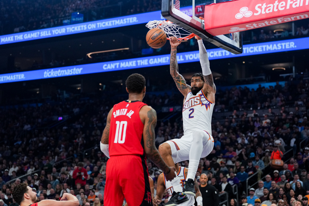 Phoenix Suns center Nick Richards (2) dunks the ball while Houston Rockets forward Jabari Smith Jr. (10) watches during the first half of an NBA basketball game, Monday, Nov. 24, 2025, in Phoenix. (AP Photo/Samantha Chow)