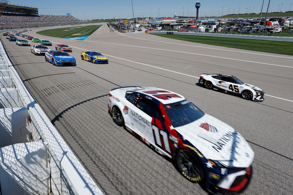 Denny Hamlin (11) and Tyler Reddick (45) lead other drivers into Turn 1 at the start of a NASCAR Cup Series auto race at Kansas Speedway in Kansas City, Kan., Sunday, April 19, 2026. (AP Photo/Colin E. Braley)