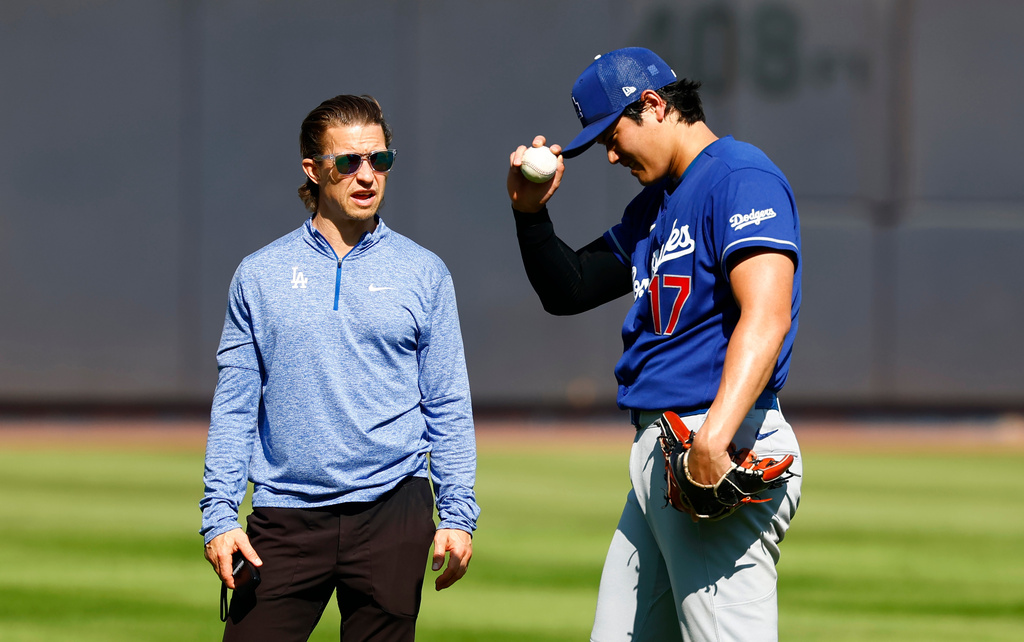 Los Angeles Dodgers' Shohei Ohtani, right, stands in the outfield with trainer Albert Thomas, left, before the second game of a baseball doubleheader against the New York Yankees, Sunday, July 19, 2026, in New York. (AP Photo/Noah K. Murray)
