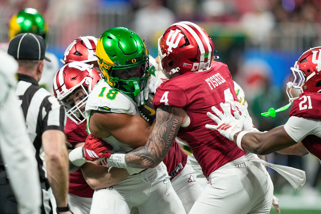 Oregon tight end Kenyon Sadiq (18) carries agasint Indiana linebacker Aiden Fisher (4) during the second half of the Peach Bowl NCAA college football playoff semifinal, Friday, Jan. 9, 2026, in Atlanta. (AP Photo/Brynn Anderson)