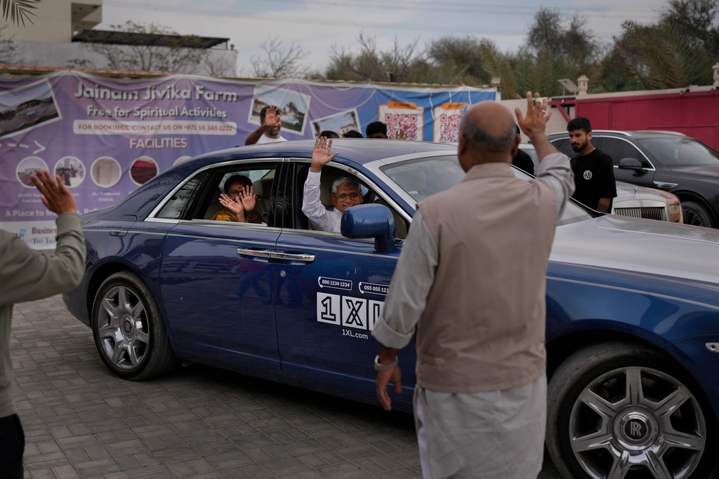 Stranded foreign travelers wave to others as they depart from the farmhouse owned by an Indian businessman, now converted into a shelter, in Ajman, near Dubai, United Arab Emirates, Saturday, March 7, 2026. (AP Photo/Altaf Qadri)