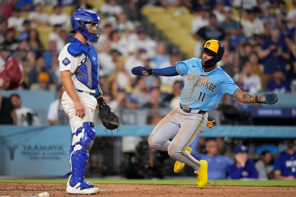 Milwaukee Brewers' Jackson Chourio, right, scores on a single by Jake Bauers as Los Angeles Dodgers catcher Ben Rortvedt watches during the ninth inning of a baseball game Thursday, Aug. 13, 2026, in Los Angeles. (AP Photo/Mark J. Terrill)
