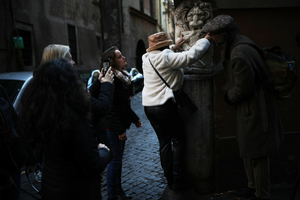 Francesca Inglese, who is blind, touches a marble relief on the corner of a building during an inclusive art tour in downtown Rome, Nov. 29, 2025. (AP Photo/Alessandra Tarantino)