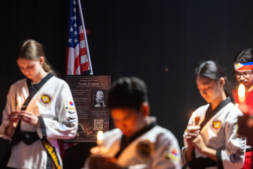 People bow their heads for a moment of silence during a candlelight mat ceremony for former student and instructor Noah Tietjens, who was killed in a drone strike at a command center in Kuwait, at Martial Arts International in Bellevue, Neb., Thursday, March 5, 2026. (Chris Machian/Omaha World-Herald via AP)