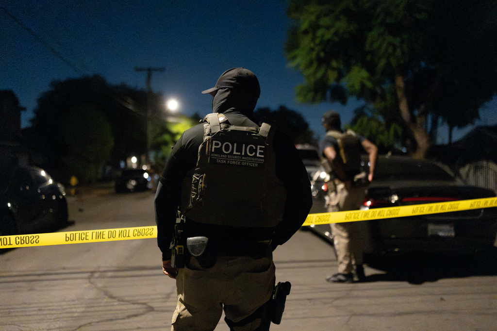 A Homeland Security Investigations task force officer stands near police tape marking a perimeter during a federal operation targeting suspected illegal voter registration in Commerce, Calif., Monday, Oct. 19, 2026. (AP Photo/Jae C. Hong)