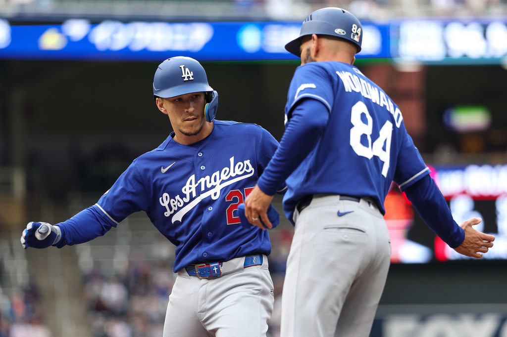 Los Angeles Dodgers' Tommy Edman celebrates his RBI single with Chris Woodward during the first inning of a baseball game against the Minnesota Twins, Tuesday, June 23, 2026, in Minneapolis. (AP Photo/Matt Krohn)