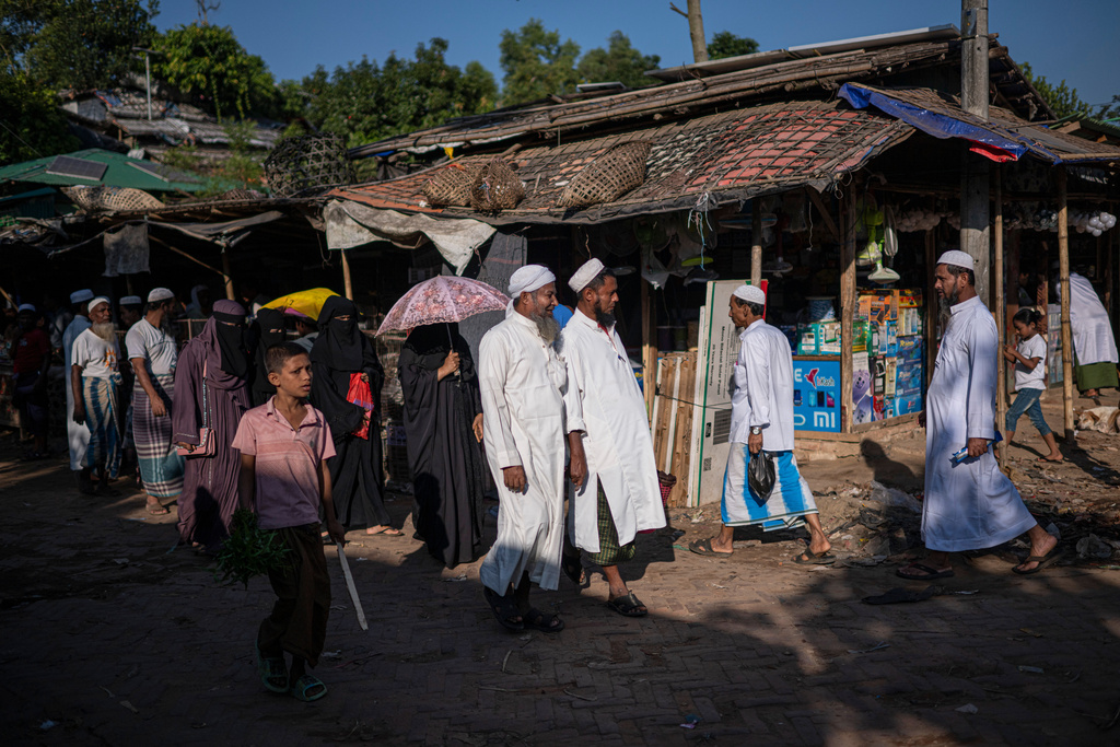 Rohingya refugees walk through a busy street inside a Rohingya refugee camp, home to over a million of Myanmar's persecuted Rohingya minority, in Cox's Bazar, Bangladesh, Monday, Nov. 24, 2025. (AP Photo/Mahmud Hossain Opu)