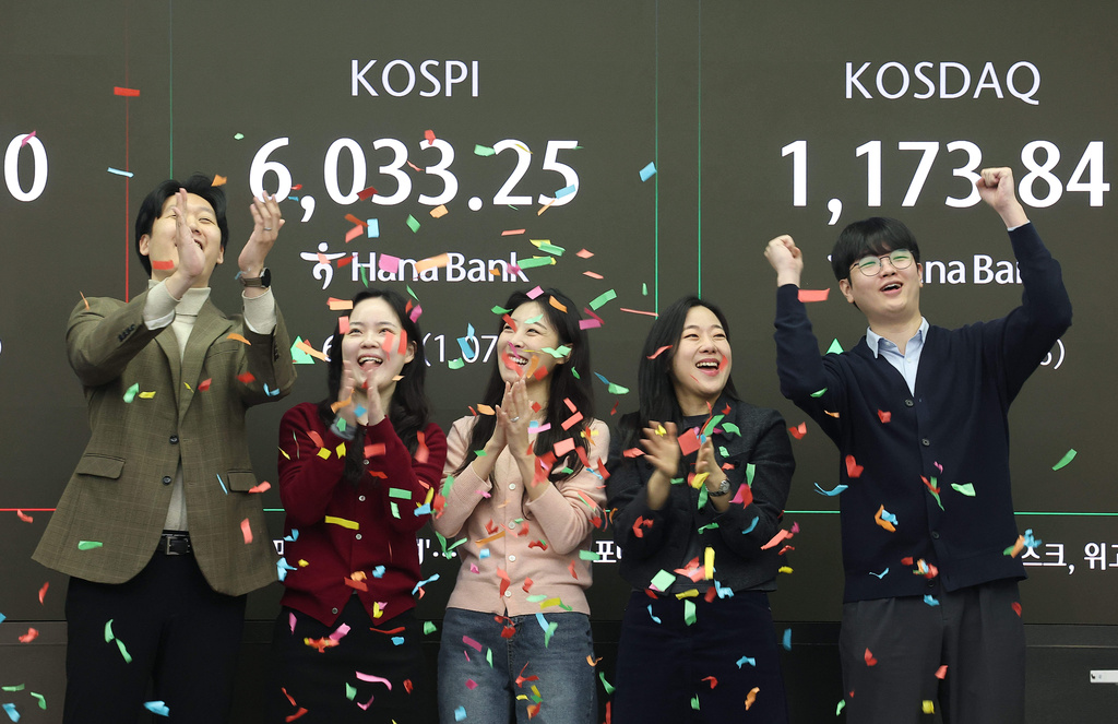 Currency traders celebrate as they work in the office with a screen showing the Korea Composite Stock Price Index (KOSPI) of over 6,000 points at a dealing room of Hana Bank in Seoul, South Korea, Wednesday, Feb. 25, 2026. (Kim Sung-min/Yonhap via AP)