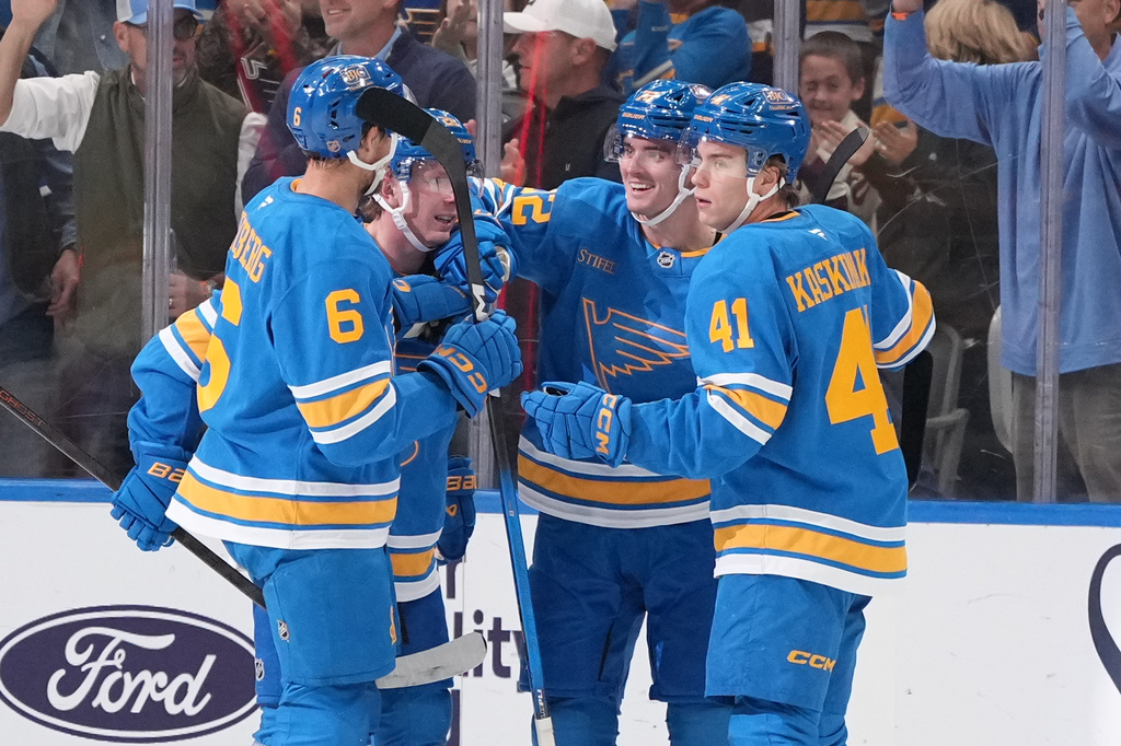 St. Louis Blues' Justin Barron is congratulated by teammates Philip Broberg (6) and Aleksanteri Kaskimaki (41) after scoring during the first period of an NHL hockey game against the Vegas Golden Knights Thursday, Oct. 22, 2026, in St. Louis. (AP Photo/Jeff Roberson)