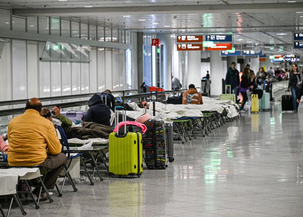 People wait on cots after drone sightings and flight cancellations at at Munich Airport, Friday, Oct.3, 2025. (Jason Tschepljakow/dpa via AP)