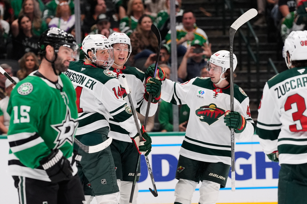 Minnesota Wild's Joel Eriksson Ek (14), Kirill Kaprizov, center rear, and Quinn Hughes (43) celebrate in front of Dallas Stars' Colin Blackwell (15) after Kaprizov scored in the second period of an NHL hockey game Thursday, April 9, 2026, in Arlington, Texas. (AP Photo/Tony Gutierrez)