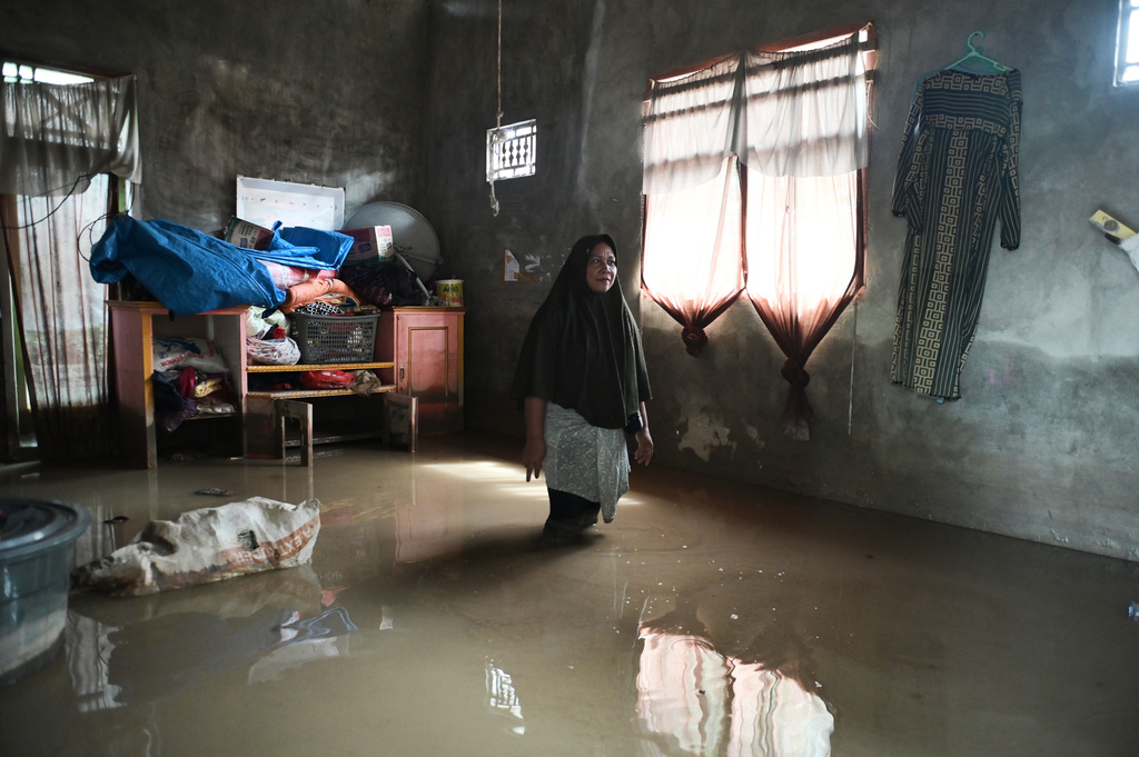 FILE - A woman stands inside her flooded house in Pidie Jaya, Aceh province, Indonesia, Wednesday, Dec. 3, 2025. (AP Photo/Reza Saifullah, File)