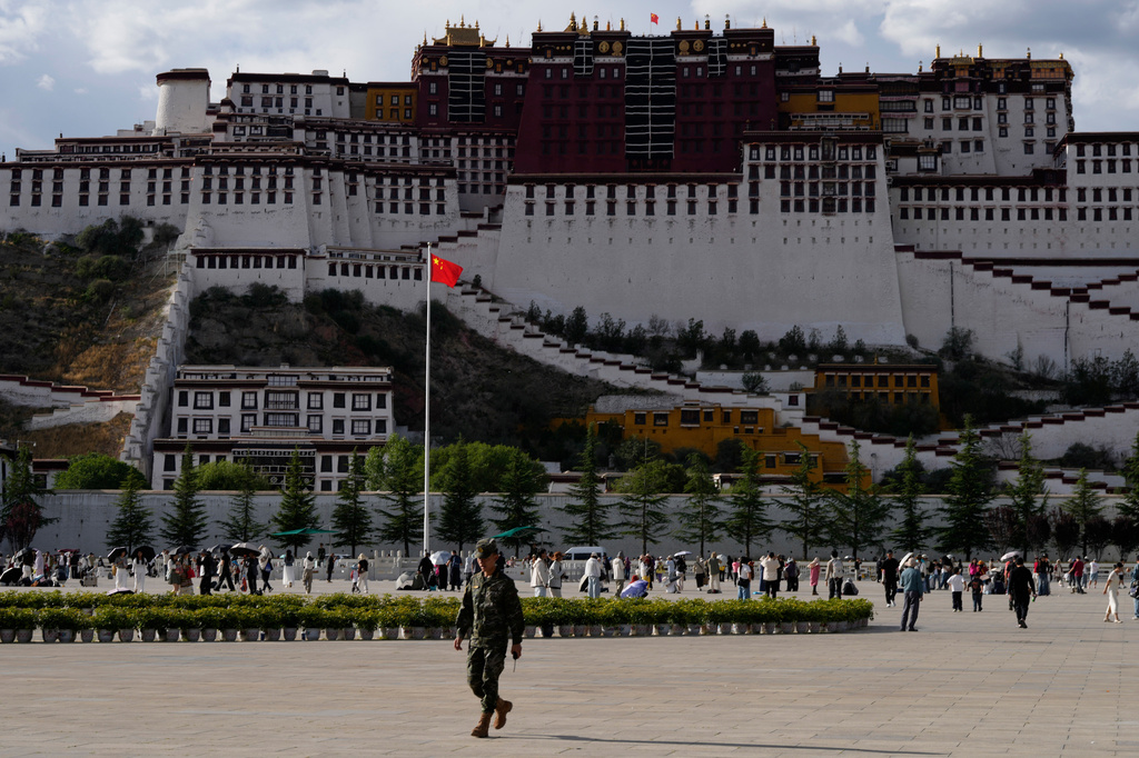 A soldier walks on a public square where a Chinese national flag hangs in front of the Potala Palace in western China's Tibet autonomous region on July 21, 2026, during a government-organized visit for foreign journalists.(AP Photo/Ng Han Guan)