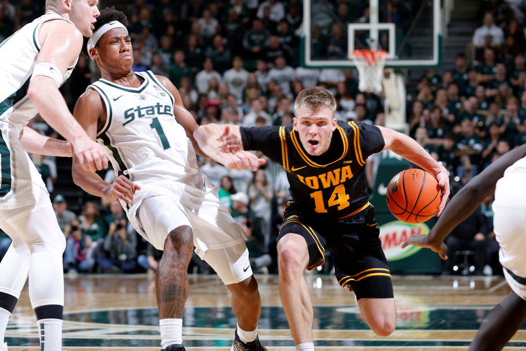 Iowa guard Bennett Stirtz (14), right, drives against Michigan State guard Jeremy Fears Jr. (1) and forward Jaxon Kohler, left, during the first half of an NCAA college basketball game, Tuesday, Dec. 2, 2025, in East Lansing, Mich. (AP Photo/Al Goldis)
