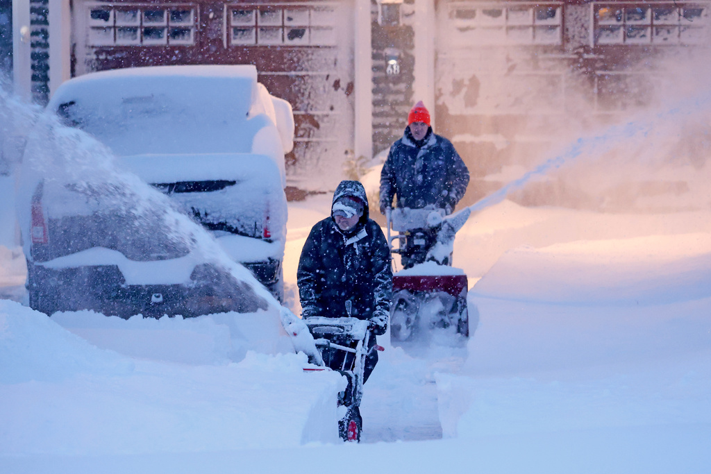 Neighbors team up to clear a driveway, Monday, Feb. 23, 2026, in North Attleborough, Mass. Over two feet of snow fell on the area after a blizzard passed through. (AP Photo/Mark Stockwell)