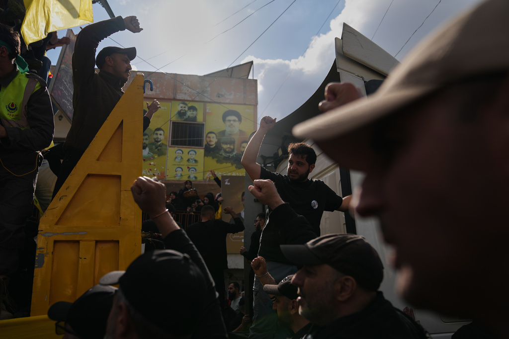 Mourners raise their fists during the funeral procession for Hezbollah fighters killed before the ceasefire in the war with Israel, in Kfar Sir, southern Lebanon, Tuesday, April 21, 2026. (AP Photo/Hassan Ammar)