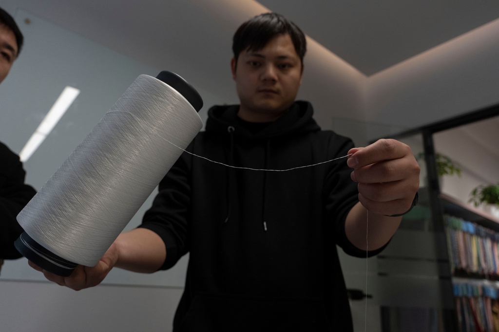A worker holds up processed polyester yarn made from recycled synthetic textile at a textile sorting facility that employ's Databeyond's Fastsort-Textile AI sorting machine in Zhangjiagang in eastern China's Jiangsu province on March 20, 2026. (AP Photo/Ng Han Guan)