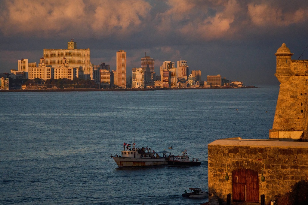 Activists wave Cuban and Palestinian flags from the vessel Maguro, arriving from Mexico with humanitarian aid as part of the "Nuestra America," or Our America Convoy, in Havana Bay, Cuba, Tuesday, March 24, 2026. (AP Photo/Ramon Espinosa)