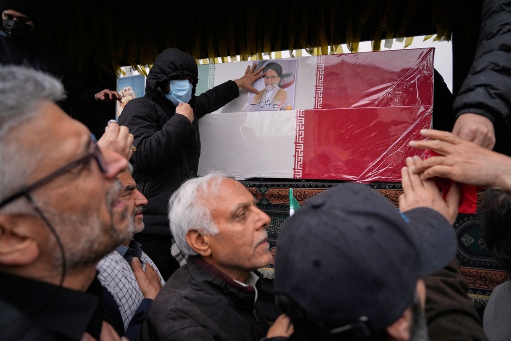 Iranians reach toward the coffins as they follow the funeral procession of Iran's intelligence minister Esmail Khatib and, according to Iranian officials, his wife and daughter, in Tehran, Iran, Friday, March 20, 2026. (AP Photo/Vahid Salemi)