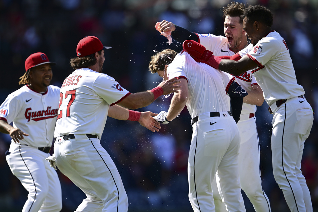 Cleveland Guardians' Kyle Manzardo, center, is congratulated by Angel Martinez, right, Nolan Jones, top, Austin Hedges (17) and Jose Ramirez, left, after driving in the game winning run in the 10th inning of a baseball game against the Tampa Bay Rays, Wednesday, Aug. 27, 2025, in Cleveland. (AP Photo/David Dermer)
