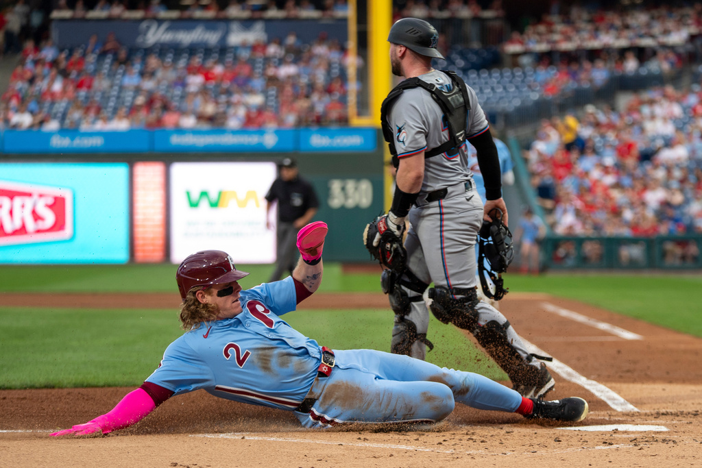 Philadelphia Phillies' Harrison Bader, left, slides safely into home on a ground out by Alec Bohm as Miami Marlins catcher Liam Hicks, right, looks on during the first inning of a baseball game, Thursday, Sept. 25, 2025, in Philadelphia. (AP Photo/Chris Szagola)