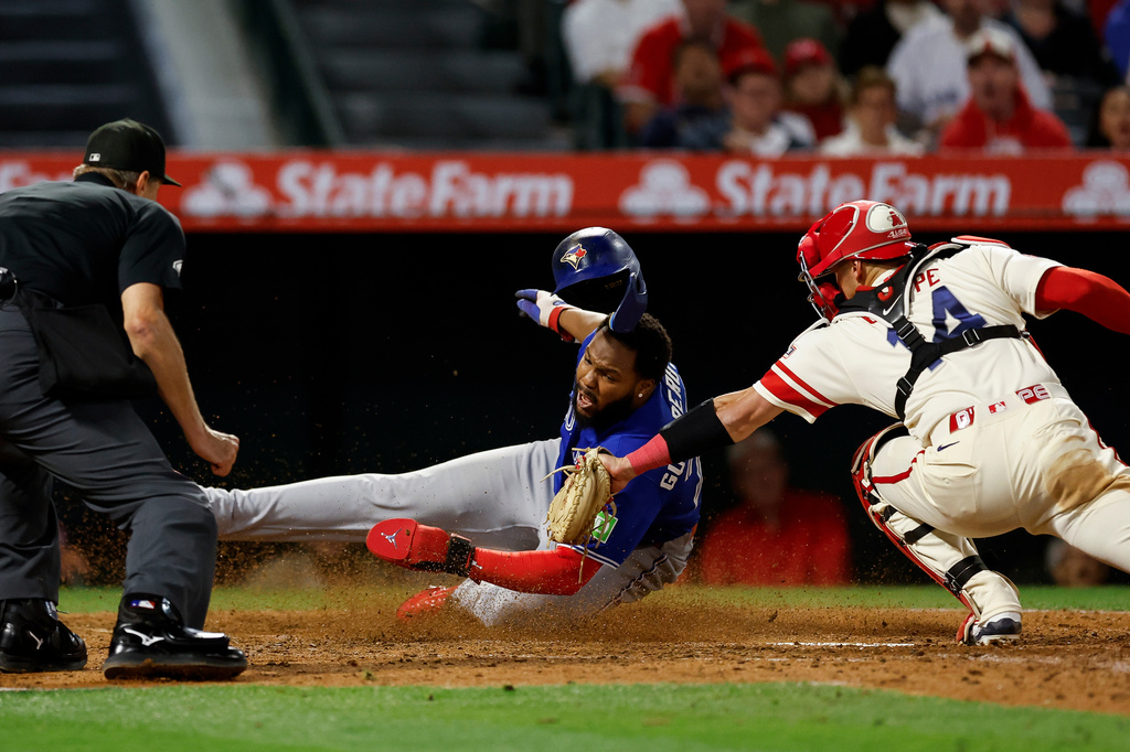 Toronto Blue Jays' Vladimir Guerrero Jr. slides into home plate as Los Angeles Angels catcher Logan O'Hoppe (14) attempts to tag him out after Blue Jays' Lenyn Sosa doubled to right field, driving in Guerrero and Ernie Clement during the eighth inning of a baseball game Tuesday, April 21, 2026, in Anaheim, Calif. (AP Photo/Caroline Brehman)