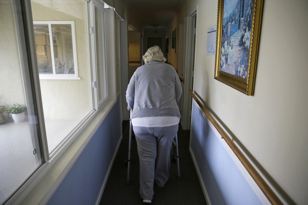 FILE - A woman uses a walker as she heads to her room at a senior care home in Calistoga, Calif., on Dec. 5, 2019. (AP Photo/Eric Risberg, File)