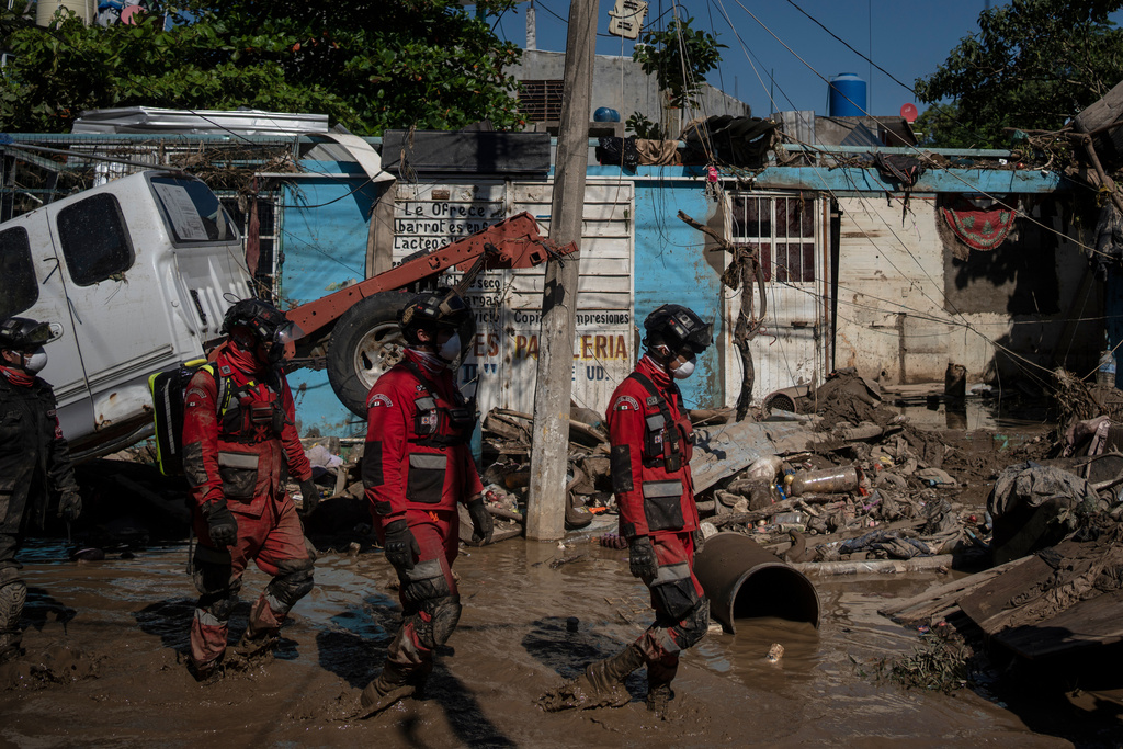 Rescue workers patrol a street in Poza Rica, Veracruz state, Mexico, Sunday, Oct. 12, 2025, after widespread flooding. (AP Photo/Felix Marquez)