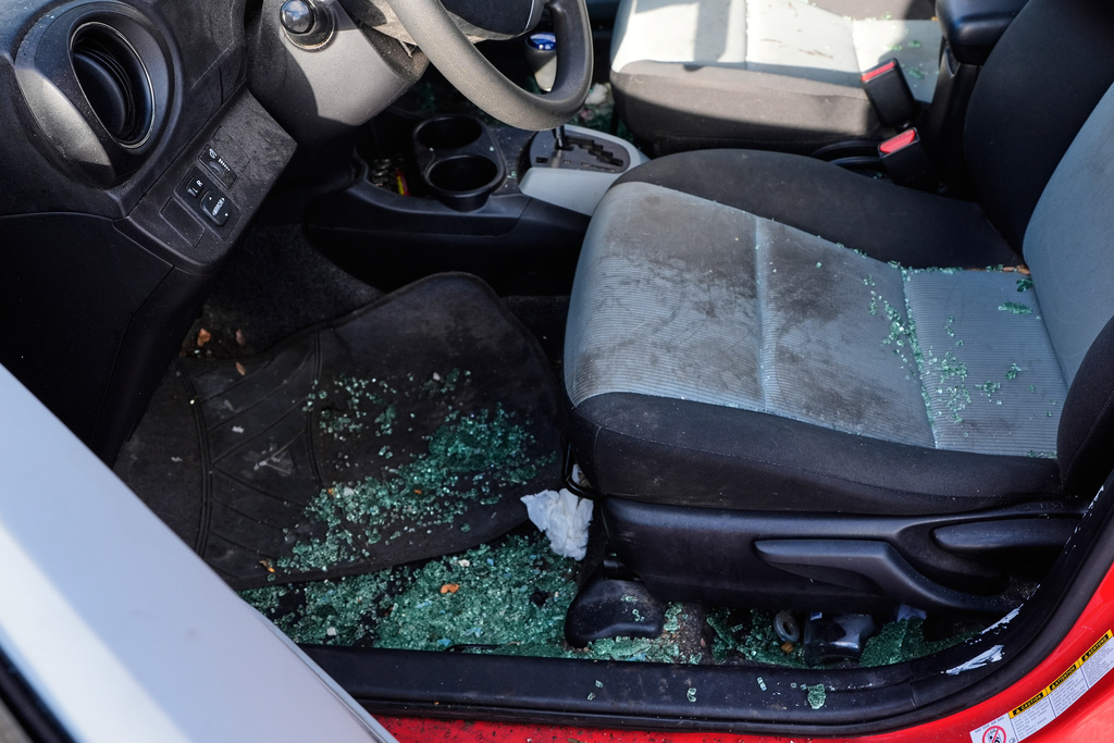 The car of Patty O'Keefe, a U.S. citizens who was arrested while following federal agents' vehicles and briefly held at a federal facility in Minneapolis, shows glass on the ground after her front driver's side window was smashed in, Tuesday, Jan. 13, 2026. (AP Photo/Jen Golbeck)