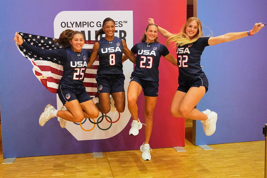 Loryn Goodwin, Ashlea Klam, Laneah Bryan and Isabella Geraci of the USA women's team jump with a United States flag during the media day ahead of the Flag Football World Championships, the sports first Olympic qualifier for LA28, in Duesseldorf, Germany, Wednesday, Aug. 12, 2026. (AP Photo/Martin Meissner)