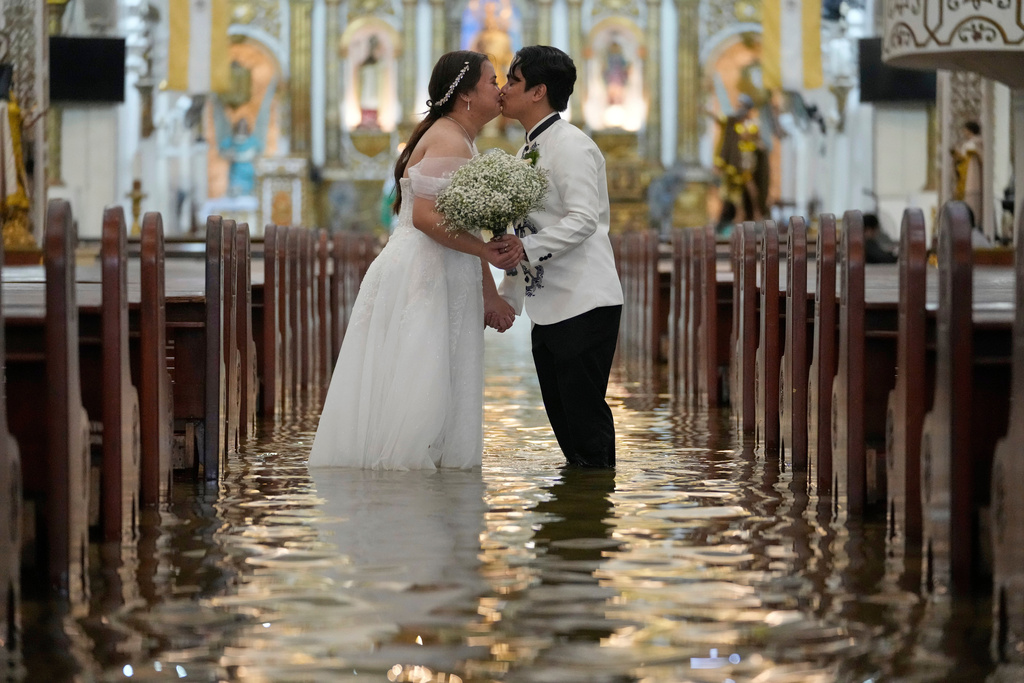 FILE - Newlyweds Jade Rick Verdillo, right, and Jamaica kiss during their wedding inside a flooded Barasoain church in Malolos, Philippines, July 22, 2025. (AP Photo/Aaron Favila, File)