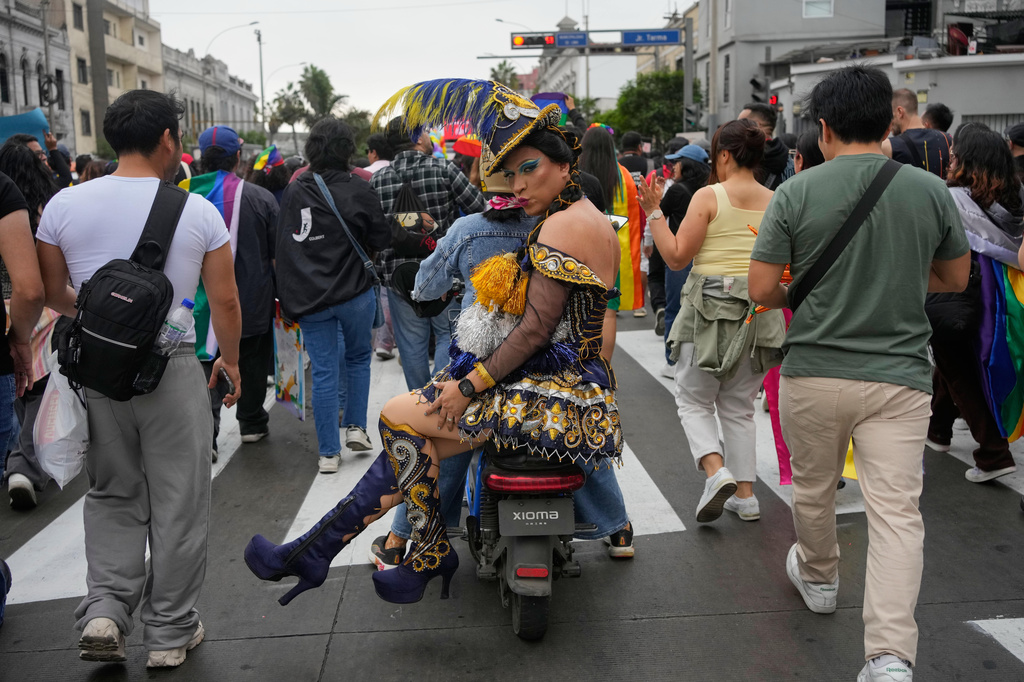 A participant blows a kiss while riding sidesaddle on a motorcycle during the Pride march in Lima, Peru, Saturday, June 27, 2026. (AP Photo/Martin Mejia)