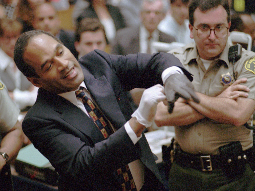 FILE - In this June 15, 1995 file photo, O.J. Simpson, left, grimaces as he tries on one of the leather gloves prosecutors say he wore the night his ex-wife Nicole Brown Simpson and Ron Goldman were murdered in a Los Angeles courtroom. (AP Photo/Sam Mircovich, Pool, file)