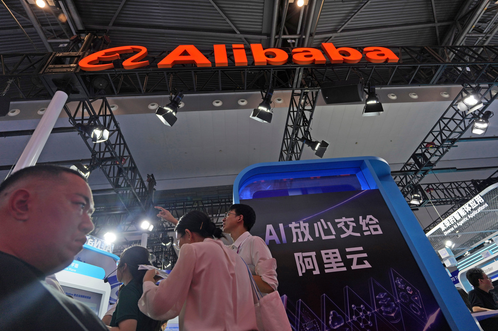 Attendees pass by the Alibaba booth near a display which reads "Rest assured giving AI to Ali Cloud" at the World AI Conference held in Shanghai on July 17, 2026. (AP Photo/Ng Han Guan)