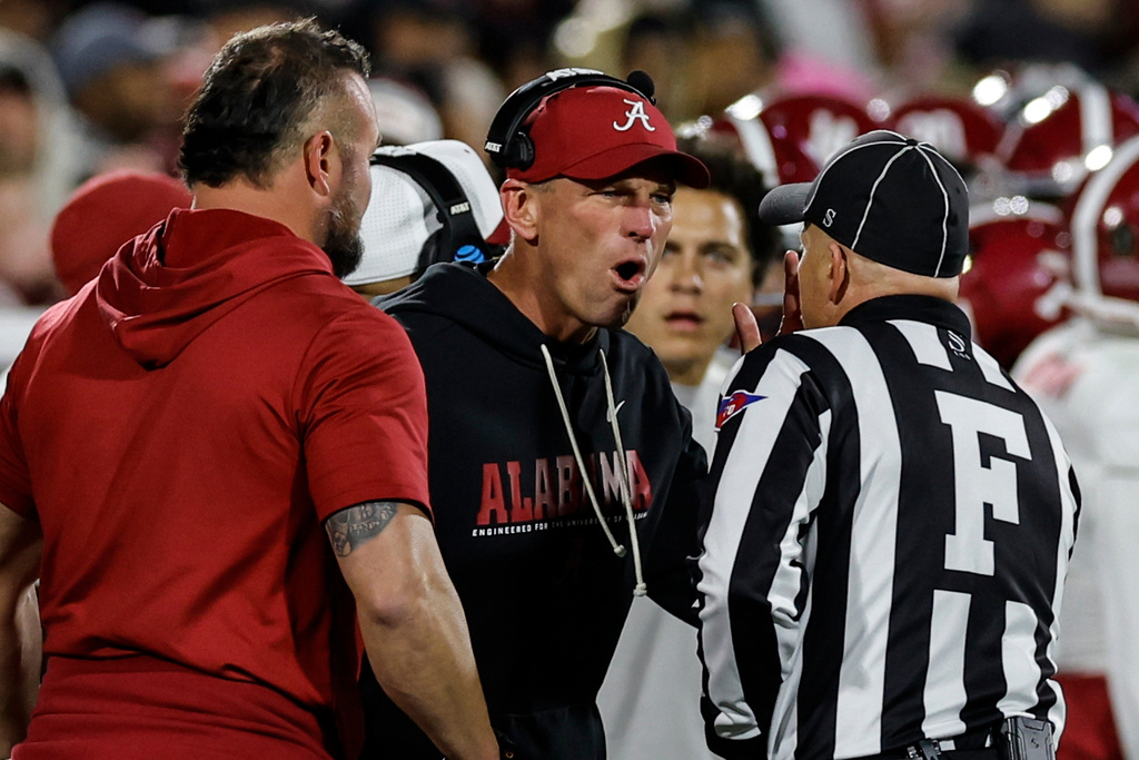 Alabama head coach Kalen Deboer, center, speaks with an official during the first half in the first round of an NCAA College Football Playoff against Oklahoma, Friday, Dec. 19, 2025, in Norman, Okla. (AP Photo/Alonzo Adams)