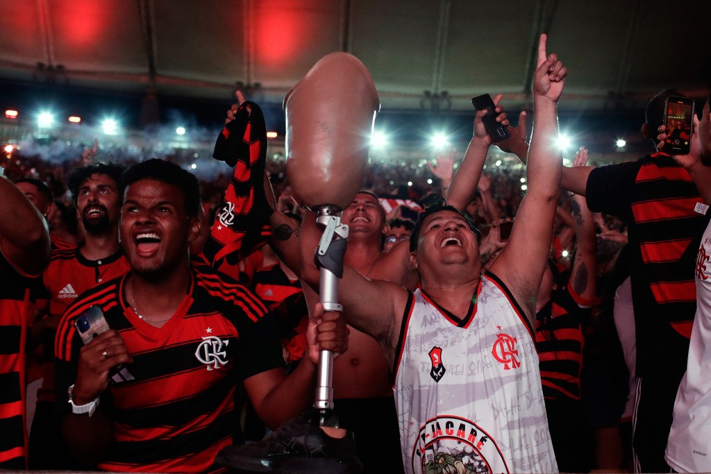 FILE - A man holds up his prosthetic leg amid fans of Brazil's Flamengo cheering as their team wins the Copa Libertadores final soccer match against Brazil's Palmeiras, being played in Lima, Peru, played on a giant screen set up at Maracana stadium in Rio de Janeiro, Nov. 29, 2025. (AP Photo/Bruna Prado, File)