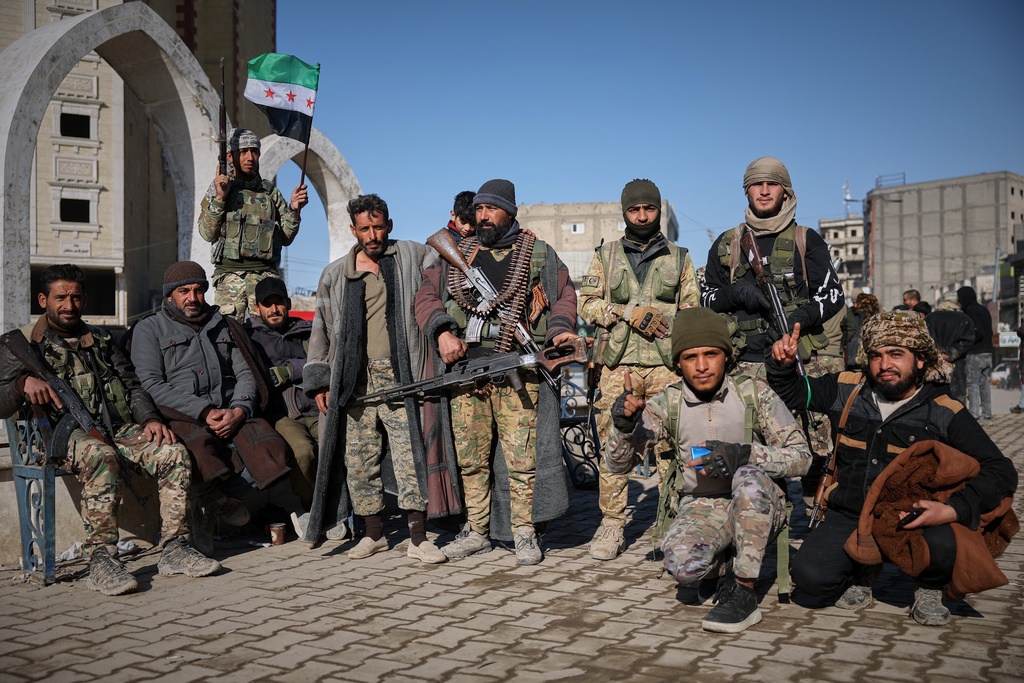 Tribal fighters pose for photographs taken by onlookers after Syrian government troops, supported by allied tribal forces, took control of Raqqa from the Syrian Democratic Forces (SDF) last Sunday at Al-Naeem roundabout in central Raqqa, northeastern Syria, Tuesday, Jan. 20, 2026. (AP Photo/Ghaith Alsayed)