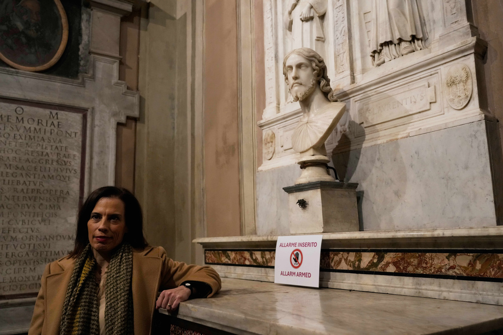 Italian researcher Valentina Salerno poses for photographers near the sculpted bust held inside the Basilica of Saint Agnes Outside the Walls, in Rome, Italy, Wednesday, March 4, 2026, which, in light of new studies, may be reattributed to Michelangelo Buonarroti. (AP Photo/Gregorio Borgia)