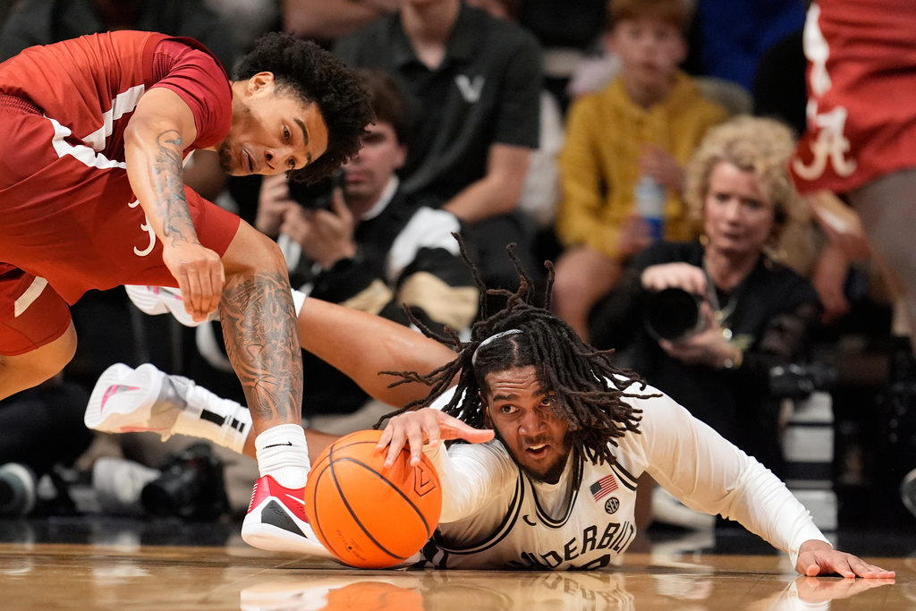 Alabama guard Jalil Bethea, left, and Vanderbilt forward Devin McGlockton, right, dive for a loose ball during the first half of an NCAA college basketball game Wednesday, Jan. 7, 2026, in Nashville, Tenn. (AP Photo/George Walker IV)