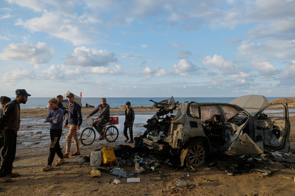 Palestinians looks at a destroyed car following an Israeli strike in Gaza City, Saturday, Dec. 13, 2025. (AP Photo/Jehad Alshrafi)