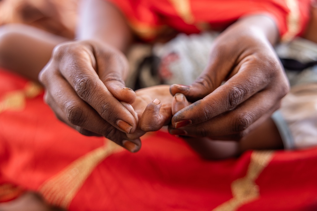 A mother holds the hand of her daughter, which has not unclenched in the eight months since fleeing mercenaries in Mali and finding refuge in Douankara, Hodh El Chargui Region, Mauritania, Nov. 8, 2025. (AP Photo/Caitlin Kelly)