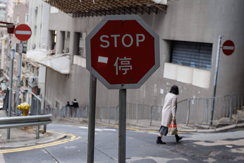 A woman carrying a red shopping bag with fruits walks past a stop sign ahead of the Lunar New Year in Hong Kong, Feb. 9, 2026. (AP Photo/May James)