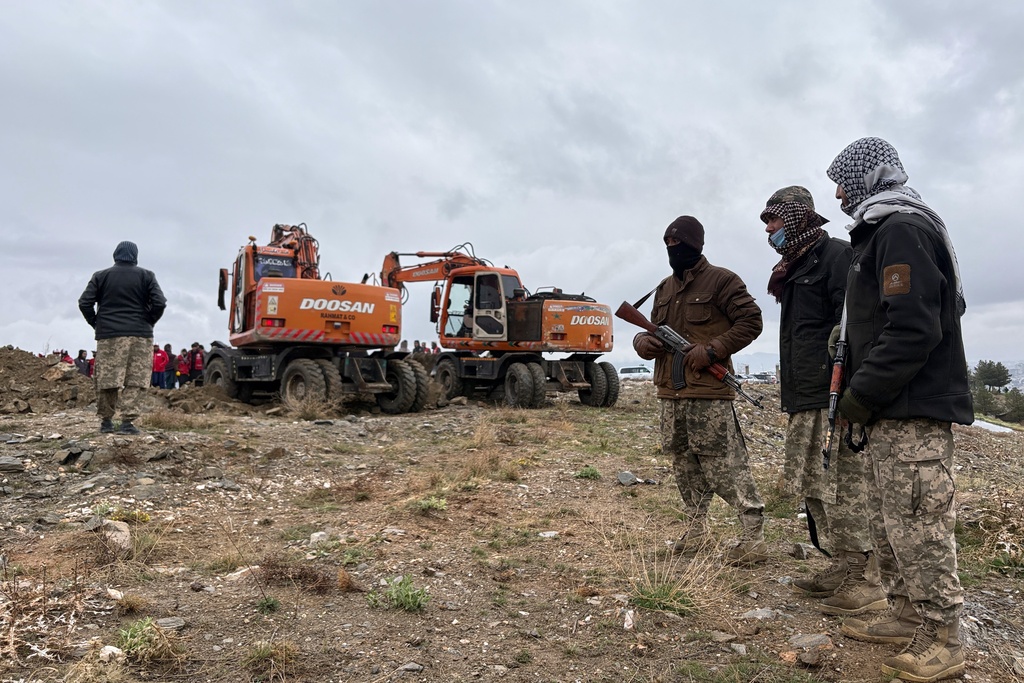 Taliban security personnel stand by as bulldozers dig graves for victims of a Monday airstrike on a drug rehabilitation hospital in Kabul, Afghanistan, Wednesday, March 18, 2026. (AP Photo/Siddiqullah Alizai)