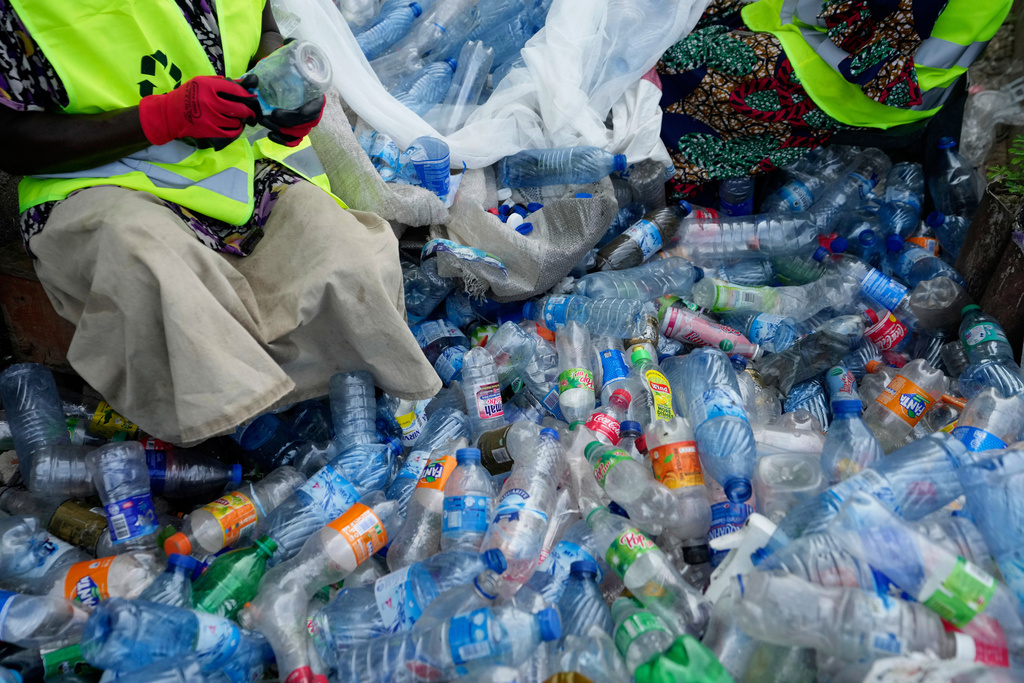 Workers use razor blades to scrape off labels from different soft-drink plastic bottles at the Street Waste Company in Lagos, Nigeria, Monday, Aug 11, 2025. (AP Photo/Sunday Alamba)