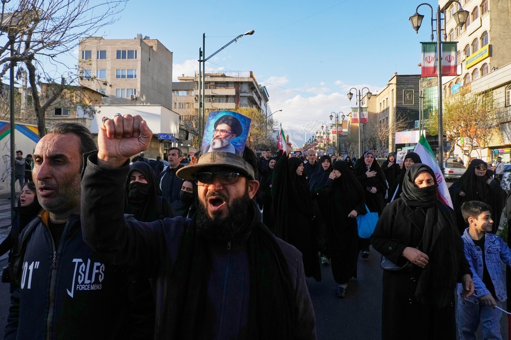 A man wearing a hat bearing a picture of the late Iranian Supreme Leader Ayatollah Ali Khamenei marches with a group of government supporters toward Khamenei's residency in Tehran, Iran, Sunday, March 1, 2026, following the confirmed death of Khamenei in U.S. and Israeli strikes. (AP Photo/Vahid Salemi)